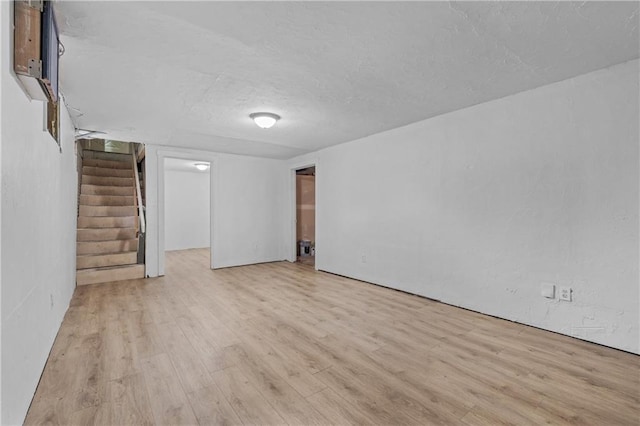 600 W Powahatan Ct, Independence, MO 64056 - unfurnished living room featuring stairs, light wood-style flooring, and a textured ceiling