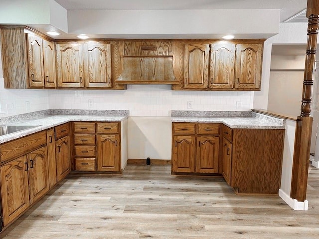 622 Morgan Dr, Stockton, MO 65785 - kitchen featuring brown cabinets, light wood finished floors, and tasteful backsplash