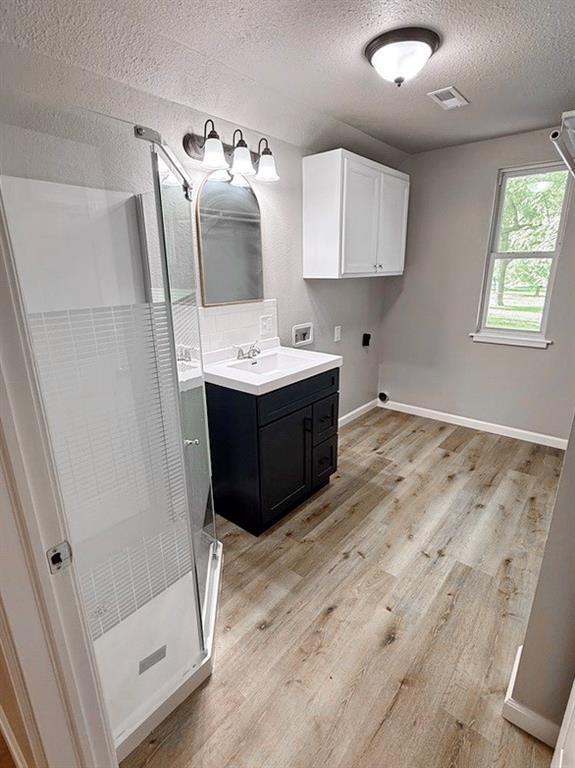 622 Morgan Dr, Stockton, MO 65785 - full bath with a textured ceiling, a stall shower, vanity, and wood finished floors
