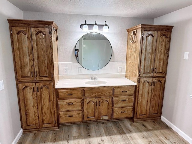 622 Morgan Dr, Stockton, MO 65785 - bathroom with wood finished floors, vanity, decorative backsplash, and a textured ceiling