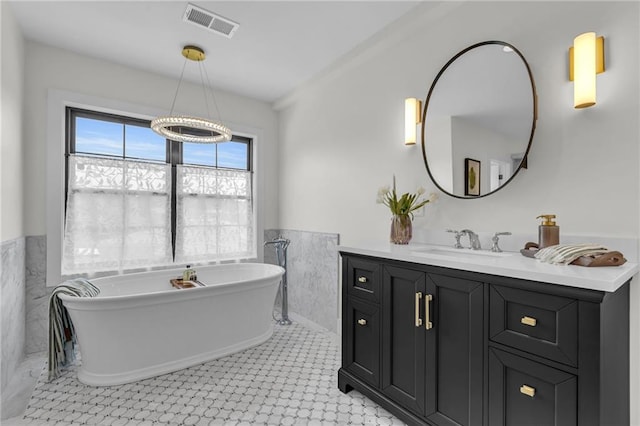 12811 W 71st St, Shawnee, KS 66216 - bathroom featuring a wainscoted wall, vanity, a freestanding bath, tile walls, and a chandelier