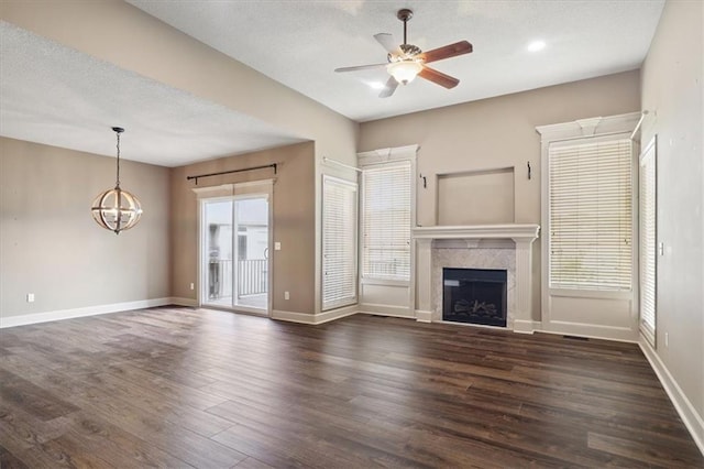 5214 NE 70th St, Kansas City, MO 64199 - unfurnished living room with a ceiling fan, a chandelier, dark wood finished floors, a fireplace, and a textured ceiling