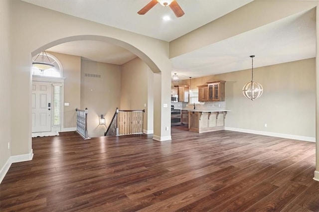 5214 NE 70th St, Kansas City, MO 64199 - unfurnished living room featuring dark wood finished floors, a ceiling fan, arched walkways, and a chandelier