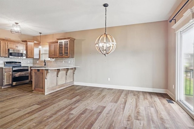 5214 NE 70th St, Kansas City, MO 64199 - kitchen with appliances with stainless steel finishes, wood finished floors, tasteful backsplash, a breakfast bar area, and healthy amount of natural light