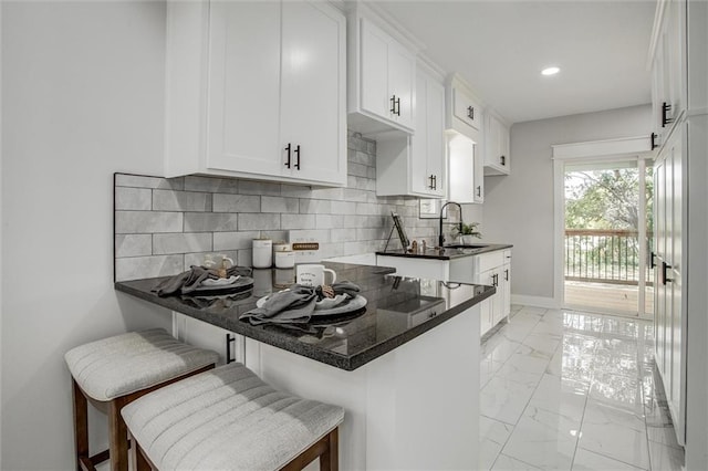 1975 Parallel Pkwy, Kansas City, KS 66104 - kitchen featuring light marble finish floors, white cabinets, tasteful backsplash, a breakfast bar, and recessed lighting