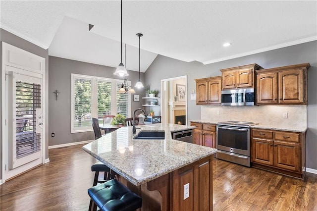 16369 S Woodstone Dr, Olathe, KS 66062 - kitchen with appliances with stainless steel finishes, vaulted ceiling, a kitchen bar, brown cabinets, and tasteful backsplash
