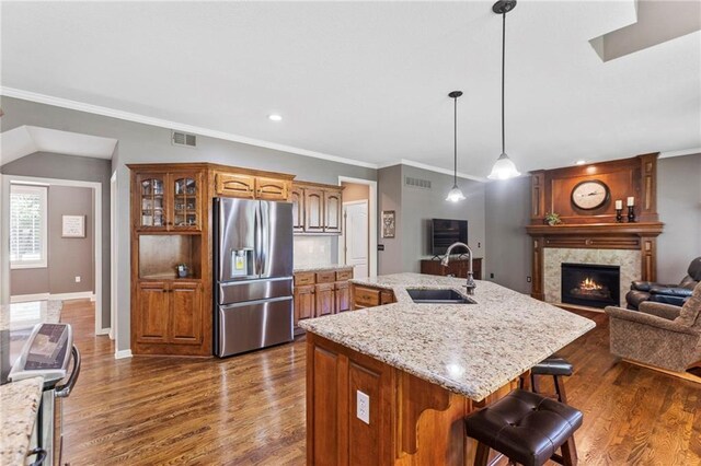 16369 S Woodstone Dr, Olathe, KS 66062 - kitchen featuring stainless steel appliances, brown cabinets, a center island with sink, a breakfast bar, and a fireplace