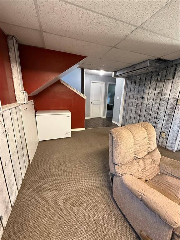 913 N Pine St, Cameron, MO 64429 - finished below grade area featuring a drop ceiling, wood walls, fridge, and carpet floors