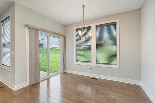 14446 Houston St, Olathe, KS 66061 - unfurnished dining area featuring a chandelier and hardwood / wood-style flooring