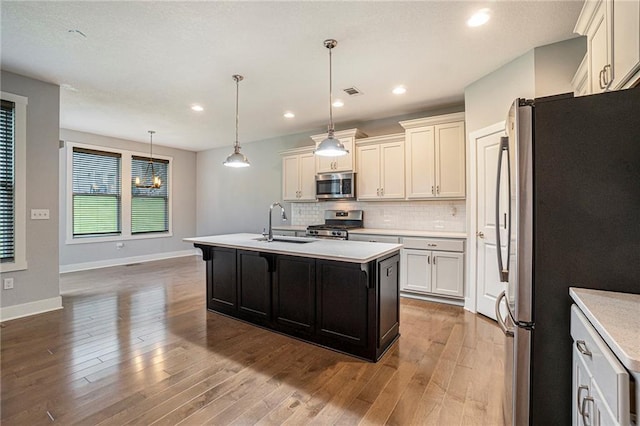 14446 Houston St, Olathe, KS 66061 - kitchen featuring stainless steel appliances, light countertops, wood finished floors, decorative backsplash, and an island with sink