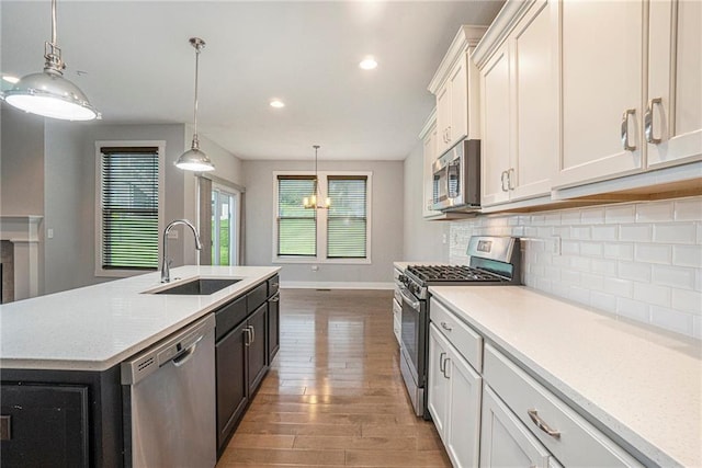 14446 Houston St, Olathe, KS 66061 - kitchen with appliances with stainless steel finishes, decorative backsplash, wood finished floors, a kitchen island with sink, and recessed lighting