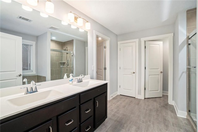 14446 Houston St, Olathe, KS 66061 - bathroom featuring a shower stall, double vanity, and wood finished floors