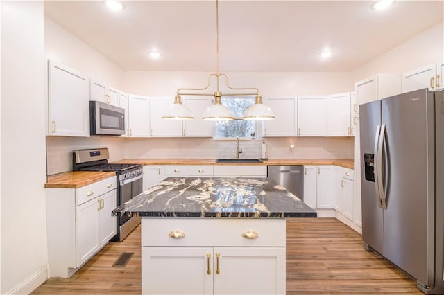 1811 Kimball Ave, Kansas City, KS 66104 - kitchen with appliances with stainless steel finishes, white cabinetry, light wood-style floors, backsplash, and recessed lighting