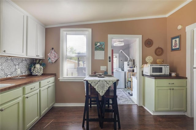 311 E Mary St, Yates Center, KS 66783 - kitchen featuring wooden counters, white microwave, green cabinets, washer / dryer, and ornamental molding