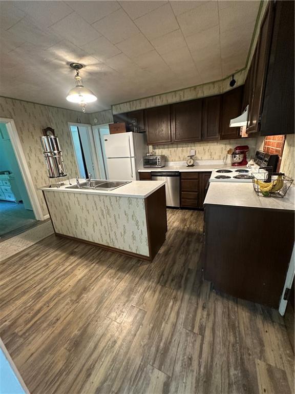 317 Chrissenger St, Burlington Junction, MO 64428 - kitchen featuring white appliances, dark wood-type flooring, range hood, light countertops, and dark brown cabinets