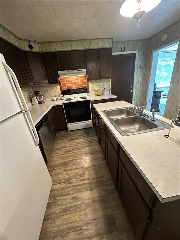 317 Chrissenger St, Burlington Junction, MO 64428 - kitchen with white appliances, under cabinet range hood, dark wood-type flooring, light countertops, and backsplash