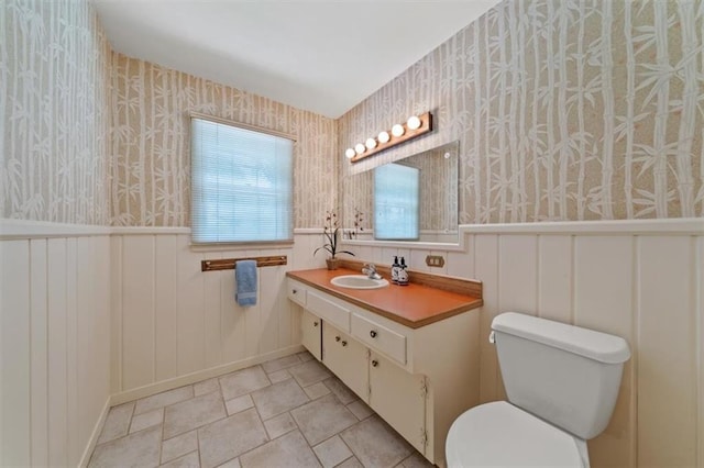 5211 W 79th Ter, Prairie Village, KS 66208 - bathroom with wallpapered walls, vanity, stone finish flooring, and a wainscoted wall
