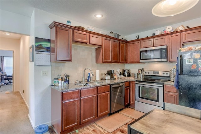 203 E Elm St, Olathe, KS 66061 - kitchen featuring stainless steel appliances, decorative backsplash, light stone countertops, brown cabinetry, and recessed lighting