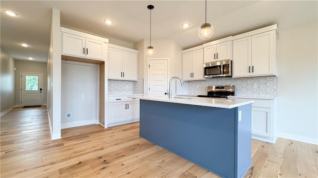 778 Creekmoor Dr, Raymore, MO 64083 - kitchen featuring stainless steel appliances, white cabinetry, light countertops, light wood-style flooring, and recessed lighting