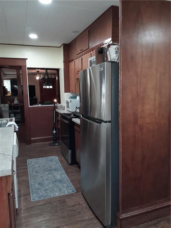 4020 Campbell St, Kansas City, MO 64110 - kitchen with stainless steel appliances, light countertops, dark wood-style floors, and brown cabinets