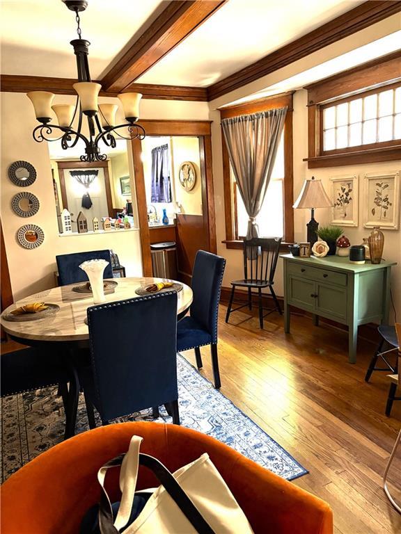 4020 Campbell St, Kansas City, MO 64110 - dining room with a chandelier, light wood-type flooring, crown molding, and beam ceiling
