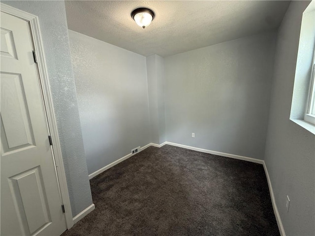 1515 S Home Ave, Independence, MO 64052 - unfurnished room featuring a textured ceiling, dark colored carpet, and a textured wall