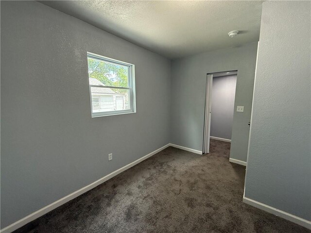 1515 S Home Ave, Independence, MO 64052 - empty room with a smoke detector, dark carpet, and a textured ceiling