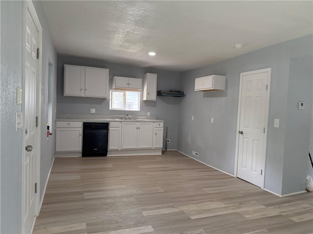 1515 S Home Ave, Independence, MO 64052 - kitchen featuring black dishwasher, white cabinets, light wood-style flooring, light countertops, and a textured ceiling