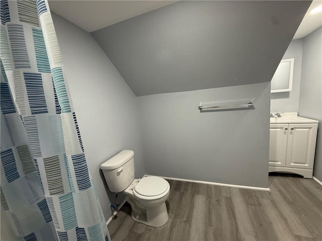 1515 S Home Ave, Independence, MO 64052 - bathroom featuring wood finished floors, vanity, vaulted ceiling, and a shower with curtain