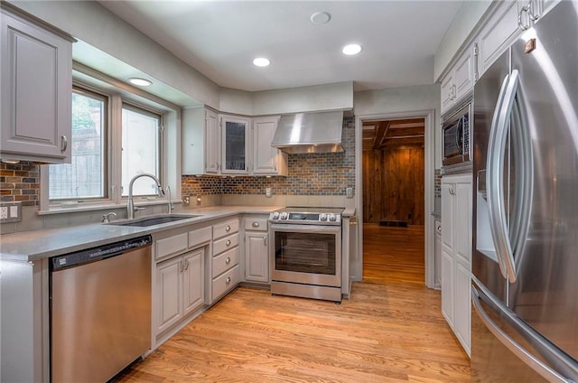 9015 Outlook Dr, Overland Park, KS 66207 - kitchen featuring appliances with stainless steel finishes, wall chimney exhaust hood, light wood-type flooring, decorative backsplash, and light countertops