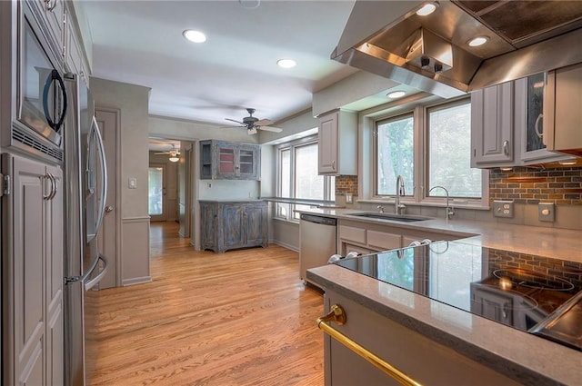 9015 Outlook Dr, Overland Park, KS 66207 - kitchen featuring appliances with stainless steel finishes, island range hood, a ceiling fan, light wood finished floors, and tasteful backsplash