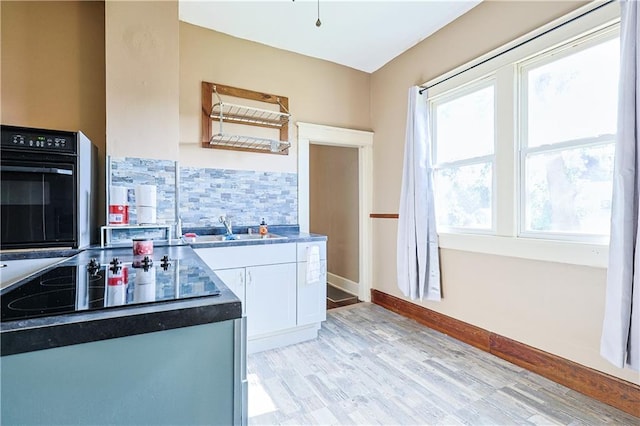 2627 Renick St, Saint Joseph, MO 64507 - kitchen with black appliances, white cabinets, tasteful backsplash, light wood-style flooring, and dark countertops