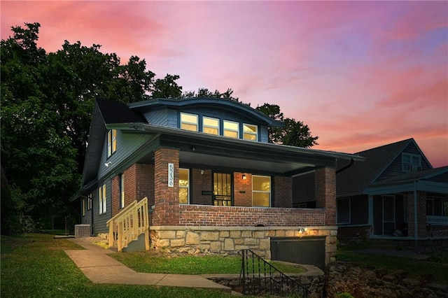 5236 Woodland Ave, Kansas City, MO 64110 - view of front of house featuring brick siding, covered porch, and a front lawn