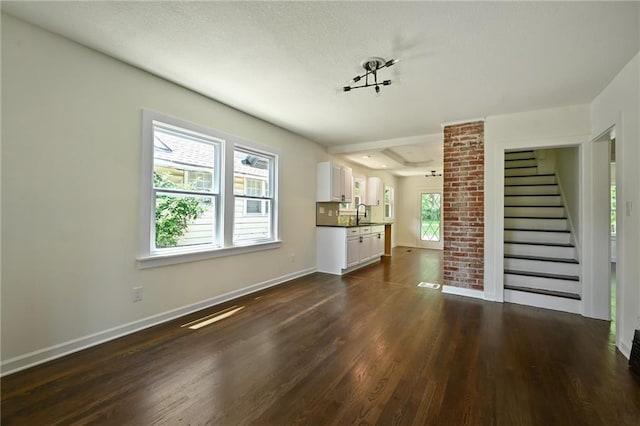 5236 Woodland Ave, Kansas City, MO 64110 - unfurnished living room with dark wood-style floors and stairs