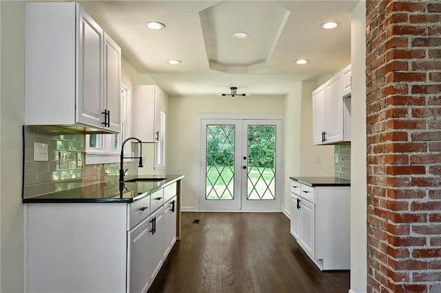 5236 Woodland Ave, Kansas City, MO 64110 - kitchen featuring dark countertops, dark wood-style floors, decorative backsplash, recessed lighting, and white cabinetry