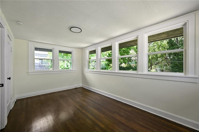 5236 Woodland Ave, Kansas City, MO 64110 - empty room featuring dark wood-type flooring, a textured ceiling, and a smoke detector