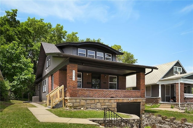 5236 Woodland Ave, Kansas City, MO 64110 - view of front of home featuring brick siding, a porch, and a front yard