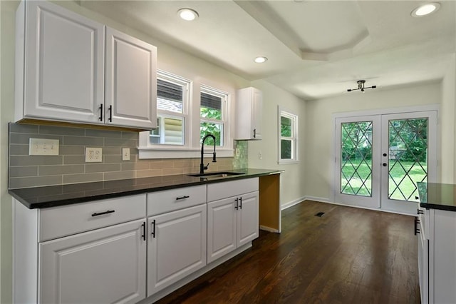 5236 Woodland Ave, Kansas City, MO 64110 - kitchen with dark countertops, french doors, dark wood finished floors, backsplash, and white cabinets