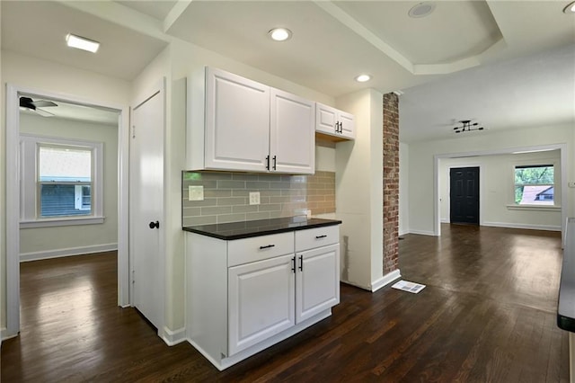 5236 Woodland Ave, Kansas City, MO 64110 - kitchen with dark countertops, dark wood-type flooring, tasteful backsplash, white cabinets, and recessed lighting