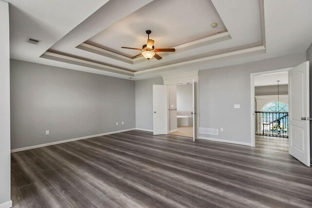 16211 S Locust St, Olathe, KS 66062 - unfurnished bedroom featuring a raised ceiling, crown molding, dark wood-style flooring, and ensuite bathroom