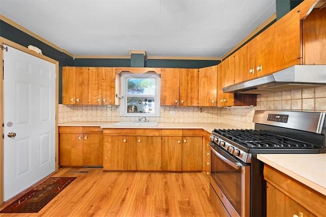 2704 Garland St, Leavenworth, KS 66048 - kitchen featuring stainless steel gas stove, under cabinet range hood, light countertops, brown cabinets, and light wood-style floors