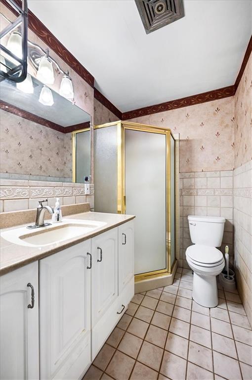 2704 Garland St, Leavenworth, KS 66048 - bathroom featuring wallpapered walls, tile walls, vanity, tile patterned floors, and a stall shower