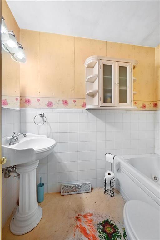 2704 Garland St, Leavenworth, KS 66048 - full bath with tile walls, a bath, and wainscoting