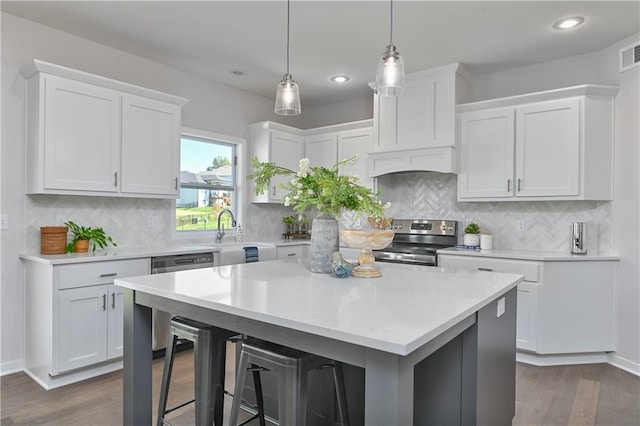 6122 Lewis Dr, Shawnee, KS 66226 - kitchen featuring appliances with stainless steel finishes, a kitchen bar, light countertops, white cabinetry, and dark wood-style flooring