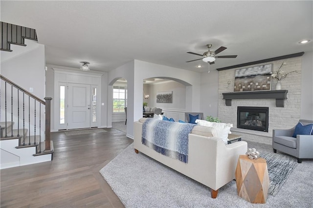 6122 Lewis Dr, Shawnee, KS 66226 - living area featuring arched walkways, stairs, ceiling fan, wood finished floors, and a fireplace