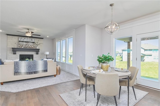 6122 Lewis Dr, Shawnee, KS 66226 - dining space featuring a fireplace, a chandelier, wood finished floors, and a ceiling fan