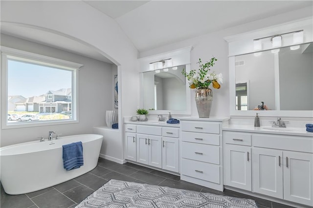 6122 Lewis Dr, Shawnee, KS 66226 - full bathroom featuring double vanity, plenty of natural light, a freestanding tub, tile patterned floors, and vaulted ceiling