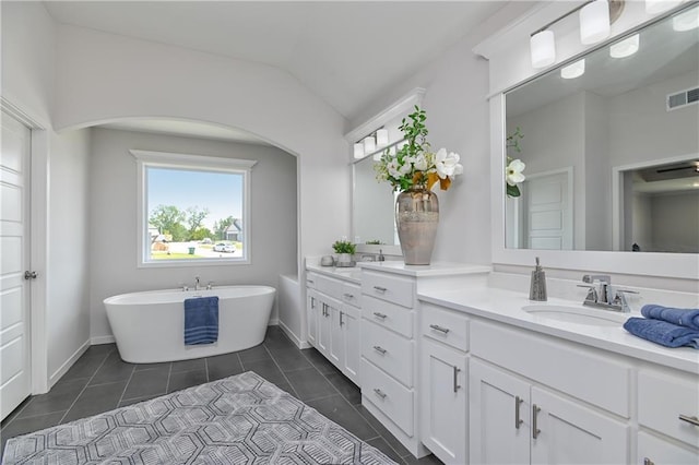 6122 Lewis Dr, Shawnee, KS 66226 - full bathroom featuring double vanity, vaulted ceiling, a freestanding tub, and tile patterned flooring