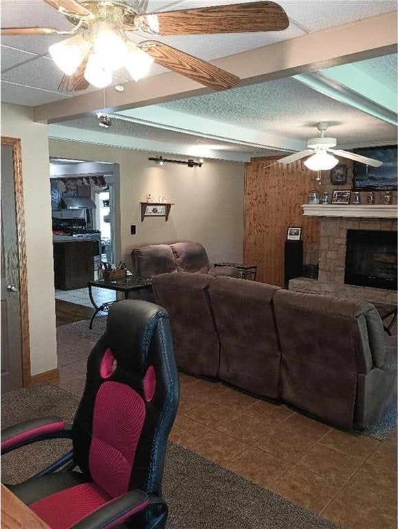 1712 S Hands St, Independence, MO 64055 - tiled living area featuring ceiling fan, a stone fireplace, and beamed ceiling