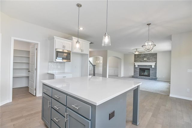 6108 Lewis Dr, Shawnee, KS 66226 - kitchen with stainless steel microwave, white cabinetry, ceiling fan, arched walkways, and light wood-type flooring